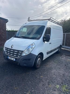 La camionnette blanche est garée sur le parking, à côté d'un bâtiment en briques.