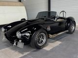 a black sports car parked in a garage next to a white van