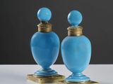 une paire de vases en verre bleu avec des socles en laiton, posés sur une surface blanche