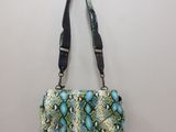 a green and white snake skin purse hanging on a wall