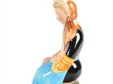 a figurine of a woman sitting on a rock