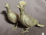 two metal birds that are sitting on a table
