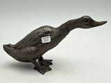 un petit canard en métal avec une étiquette autour du cou
