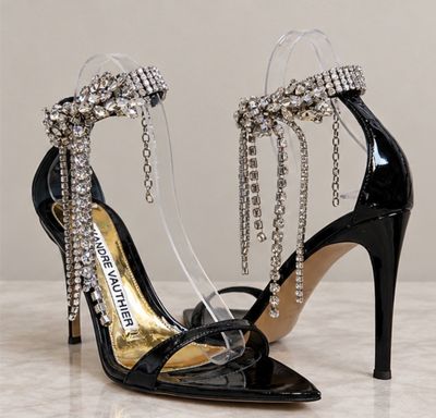 a close up of a pair of black high heels with chains on them