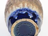 a close up of a blue and red vase on a white surface