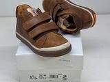 brown leather baby shoes with velcro straps on top of a white box
