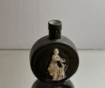 a small black vase with a picture of a woman on it
