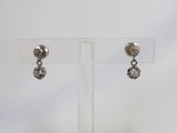 une paire de boucles d'oreilles en argent posée sur un présentoir transparent