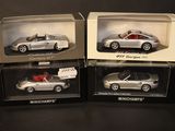three boxed silver model cars in boxes on a black surface
