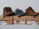 three pairs of hiking shoes sitting on top of boxes on a table