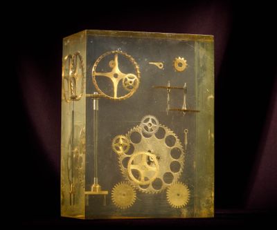une boîte en verre posée sur une table, contenant des engrenages