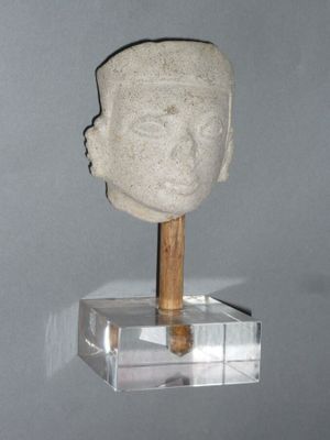 a stone head with a wooden stick on a stand