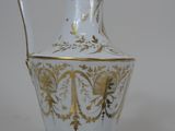 a white and gold vase sitting next to a black object