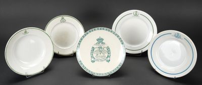 six assiettes blanches et bleues ornées d'un blason, posées sur un fond noir