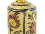 un vase jaune orné de fleurs, posé sur un fond blanc