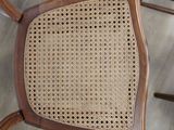 the back of a wooden chair with a woven seat and back rest