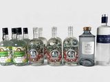 Des bouteilles de gin sont alignées sur une surface blanche