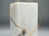 un bloc de marbre blanc sur lequel est posé un collier en fil d'or