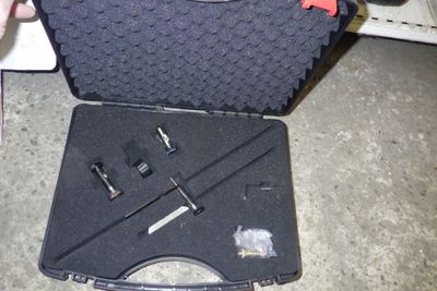 une mallette noire contenant des outils, posée par terre