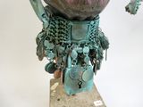 une sculpture représentant un vase posé sur un socle et entouré d'une chaîne