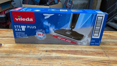 La boîte d'un balai aspirateur est posée sur une table en bois