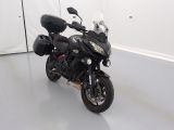 une moto noire garée dans une pièce aux murs blancs