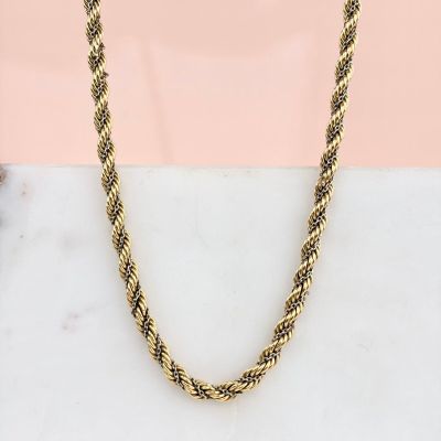 une photo d'un collier à chaîne en or posé sur une surface en marbre