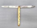 a close up of a knife with a gold handle on a gray surface