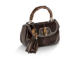 un sac à main en cuir marron muni d'une anse en bambou et de pompons
