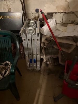 une photo d'une chambre en désordre avec un radiateur et une chaise