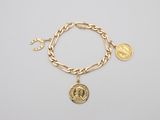 a gold bracelet with a coin and a coin charm on it