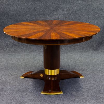 une table de salle à manger ronde avec un plateau en bois et des finitions en laiton