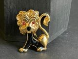 a gold lion brooch with red eyes sitting on a table