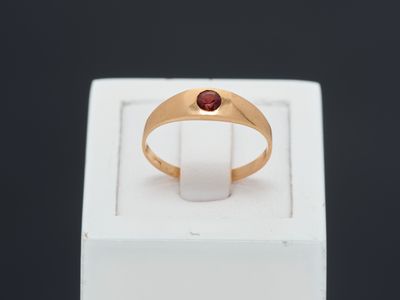 a close up of a gold ring with a red stone in it
