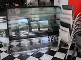 des tables et des chaises dans un restaurant au sol à carreaux et doté d'une vitrine