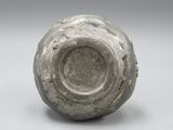 un vase gris posé sur une table, sur fond blanc
