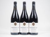 trois bouteilles de vin sont posées sur une surface blanche