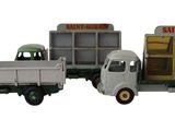 trois camions miniatures placés les uns à côté des autres sur une surface blanche