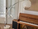 a living room with a piano, chair, lamp, and window