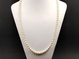 un mannequin blanc portant un collier de perles
