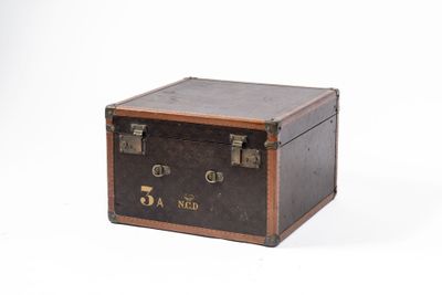 une vieille valise posée sur une surface blanche