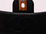 a close up of a black chanel bag with a brown handle