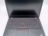 the laptop is open on a white surface and has a red button on the keyboard