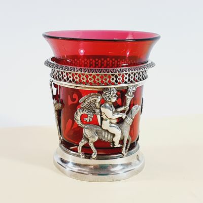 a red glass vase with a silver decoration on it