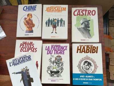 six livres posés sur une table, dont l'un se trouve devant la caméra