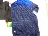 a blue jacket and a black jacket laying on a bed