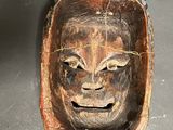 a wooden mask with a face on it on a table