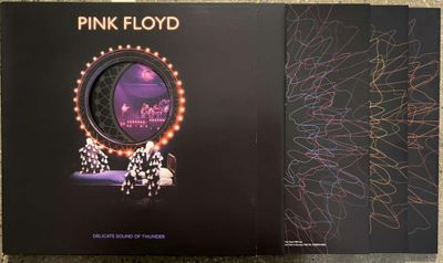 two pink floyd albums sitting on top of a table next to each other