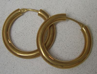 paire de boucles d'oreilles créoles dorées sur fond blanc
