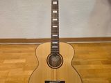 une guitare acoustique posée sur un support en bois, sur un parquet en bois massif